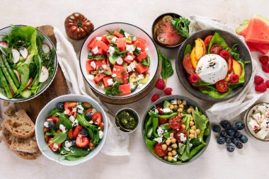 Çilekli çeşitli yaz salataları, otlar. Hafif arkaplanlı sağlıklı salata, şeftali, burrata, yabanmersini ve ceviz. Sağlıklı yemek için taze yararlı yemek. Üst görünüm.
