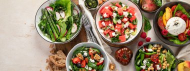 Çilekli çeşitli yaz salataları, otlar. Hafif arkaplanlı sağlıklı salata, şeftali, burrata, yabanmersini ve ceviz. Üst Manzara. Kopyalama alanı olan Panorama.