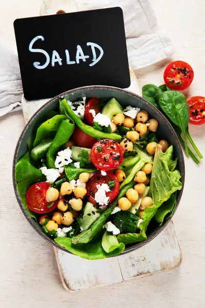 Domates, salatalık, salata, nohut ve peynirli vejetaryen nohut salatası hafif bir arka planda. Sağlıklı bir yaşam tarzı. Üst yaşam