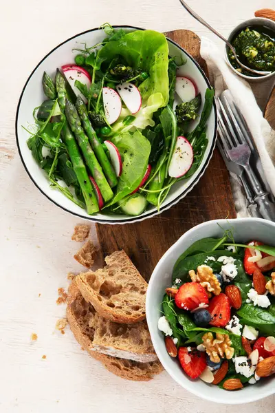 Çilekli çeşitli yaz salataları, otlar. Hafif arkaplanlı sağlıklı salata, şeftali, burrata, yabanmersini ve ceviz. Sağlıklı yemek için taze yararlı yemek. Üst görünüm.