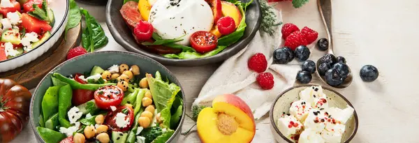 Çilekli çeşitli yaz salataları, otlar. Hafif arkaplanlı sağlıklı salata, şeftali, burrata, yabanmersini ve ceviz. Üst görünüm, alanı kopyala.