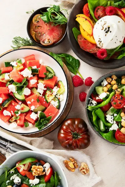 Çilekli çeşitli yaz salataları, otlar. Hafif arkaplanlı sağlıklı salata, şeftali, burrata, yabanmersini ve ceviz. Sağlıklı yemek için taze yararlı yemek. Üst görünüm.