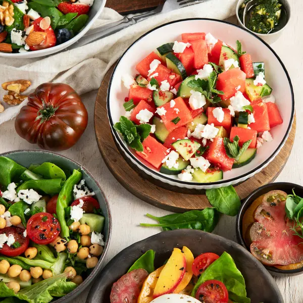 Çilekli çeşitli yaz salataları, otlar. Hafif arkaplanlı sağlıklı salata, şeftali, burrata, yabanmersini ve ceviz. Sağlıklı yemek için taze yararlı yemek. Üst görünüm.