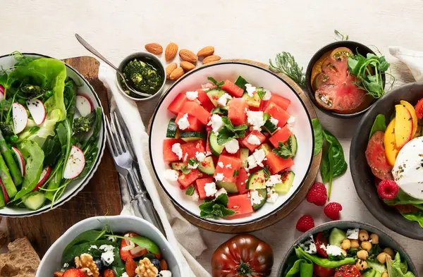Çilekli çeşitli yaz salataları, otlar. Hafif arkaplanlı sağlıklı salata, şeftali, burrata, yabanmersini ve ceviz. Üst görünüm, alanı kopyala.