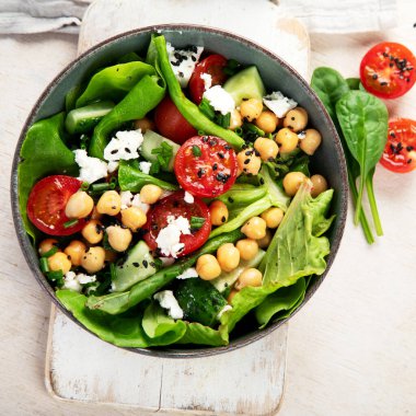 Domates, salatalık, salata, nohut ve peynirli vejetaryen nohut salatası hafif bir arka planda. Sağlıklı bir yaşam tarzı. Üst yaşam