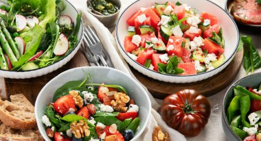 Çilekli çeşitli yaz salataları, otlar. Hafif arkaplanlı sağlıklı salata, şeftali, burrata, yabanmersini ve ceviz. Sağlıklı yemek için taze yararlı yemek. Üst görünüm.