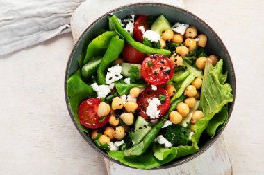 Domates, salatalık, salata, nohut ve peynirli vejetaryen nohut salatası hafif bir arka planda. Sağlıklı bir yaşam tarzı. Üst yaşam