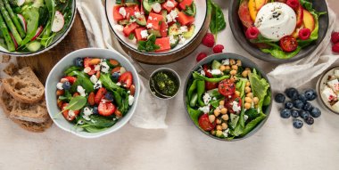 Çilekli çeşitli yaz salataları, otlar. Hafif arkaplanlı sağlıklı salata, şeftali, burrata, yabanmersini ve ceviz. Sağlıklı yemek için taze yararlı yemek. Üst Manzara. Boşluğu kopyala.