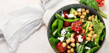 Domates, salatalık, salata, nohut ve peynirli vejetaryen nohut salatası hafif bir arka planda. Sağlıklı bir yaşam tarzı. Üst görünüm, alanı kopyala.