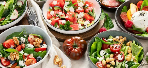 Çilekli çeşitli yaz salataları, otlar. Hafif arkaplanlı sağlıklı salata, şeftali, burrata, yabanmersini ve ceviz. Sağlıklı yemek için taze yararlı yemek. Üst görünüm.