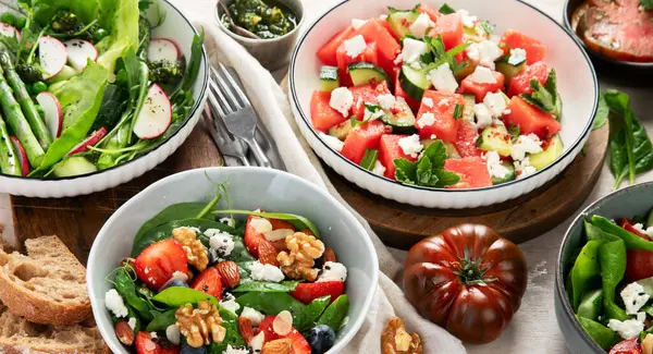 Çilekli çeşitli yaz salataları, otlar. Hafif arkaplanlı sağlıklı salata, şeftali, burrata, yabanmersini ve ceviz. Sağlıklı yemek için taze yararlı yemek. Üst görünüm.