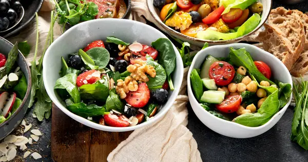 Sebzeli, meyveli ve fındıklı taze vejetaryen yaz salataları. Üst Manzara. Boşluğu kopyala.