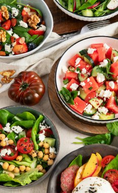 Çilekli çeşitli yaz salataları, otlar. Hafif arkaplanlı sağlıklı salata, şeftali, burrata, yabanmersini ve ceviz. Sağlıklı yemek için taze yararlı yemek. Üst görünüm.