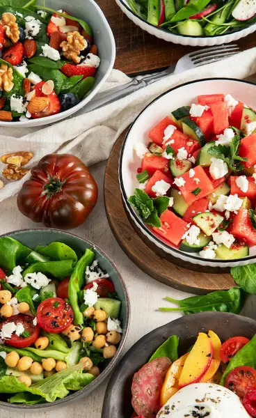 Çilekli çeşitli yaz salataları, otlar. Hafif arkaplanlı sağlıklı salata, şeftali, burrata, yabanmersini ve ceviz. Sağlıklı yemek için taze yararlı yemek. Üst görünüm.