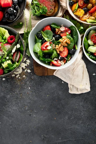 Sebzeli, meyveli ve fındıklı taze vejetaryen yaz salataları. Üst Manzara. Boşluğu kopyala.
