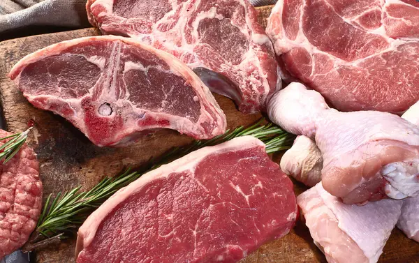 Farklı türde çiğ et, sığır eti, kuzu eti, ahşap bir tahtanın üzerinde tavuk. Üst Manzara. Panorama.