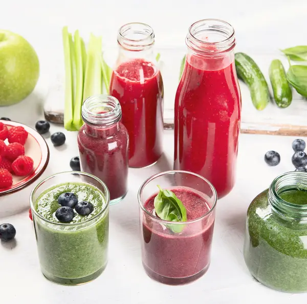 Taze meyve ve sebze içecekleri beyaz arka planda cam şişelerde. Sağlıklı beslenme ve detoks konsepti. Üst görünüm.