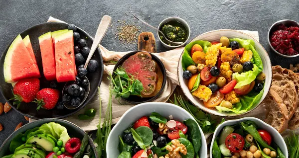 Sebzeli, meyveli ve fındıklı taze vejetaryen yaz salataları. Üst Manzara. Boşluğu kopyala.