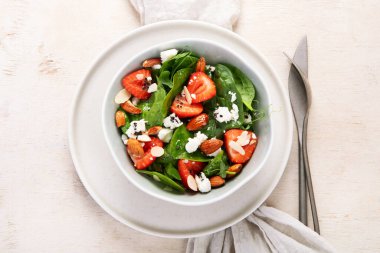 Ispanak ve çilekli yaz salatası süzme peynir ve hafif arka planda badem. Üst görünüm. 