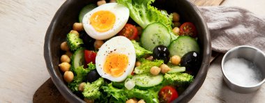 Sebze salatası, domates, salatalık, zeytin ve hafif arka planda haşlanmış yumurta. Moda yemeği. Üst Manzara. Panorama.