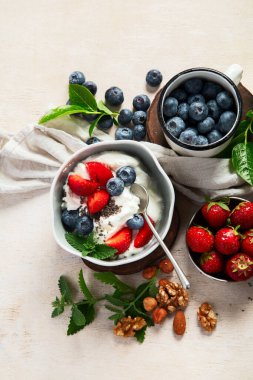 Sağlıklı kahvaltı için organik malzemeler - yoğurt, fındık, taze meyve, yulaf ezmesi, beyaz arka planda tam tahıl gevreği. Üst görünüm.