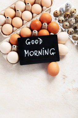 Açık arkaplanda farklı yumurtalar bulunan yumurta kutuları. Karton pakette taze organik tavuk yumurtaları veya yumurta kabı. Üst Manzara. Boşluğu kopyala.