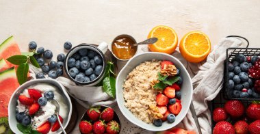 Sağlıklı kahvaltı için organik malzemeler - yoğurt, fındık, taze meyve, yulaf ezmesi, beyaz arka planda tam tahıl gevreği. Üst Manzara. Kopyalama alanı olan Panorama.