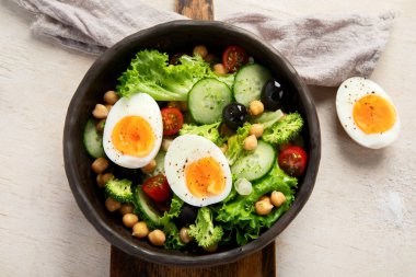 Sebze salatası, domates, salatalık, zeytin ve hafif arka planda haşlanmış yumurta. Moda yemeği. Üst görünüm.