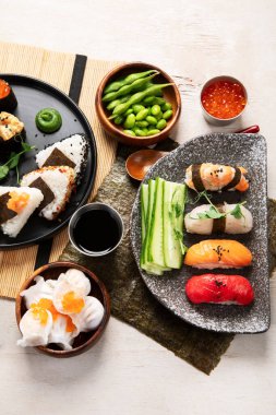 Geleneksel Japon mutfağı. Suşi, somon balığı, ton balığı ve sebzeli, hafif bir arka planda servis ediliyor. Asya yemekleri. Üst görünüm
