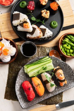 Geleneksel Japon mutfağı. Suşi, somon balığı, ton balığı ve sebzeli, hafif bir arka planda servis ediliyor. Asya yemekleri. Üst görünüm