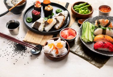 Geleneksel Japon mutfağı. Suşi, somon balığı, ton balığı ve sebzeli, hafif bir arka planda servis ediliyor. Asya yemekleri. Üst Manzara. Boşluğu kopyala.