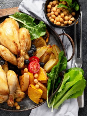 Koyu arkaplanda patates, salata ve sebzeli kızarmış tavuk. Üst görünüm.