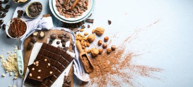 Koyu acı çikolata, kakao yağı, kakao tozu ve mavi arka planda kakao çekirdeği. Çikolata arkaplanı. Panorama, bayrak