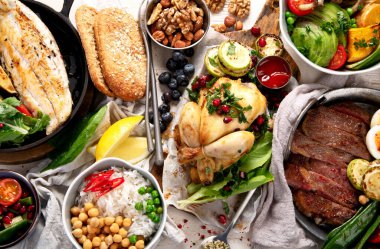 Et ızgara, balık, kızarmış patates, sebze, salata ve soslu yemek masası. Üst görünüm.