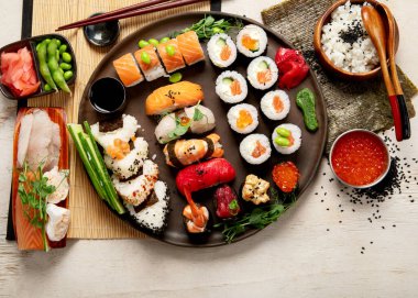 Somon, ton balığı ve sebzeli suşi ruloları bir tabakta servis edilir. Hafif arka planda Asya yemekleri. Üst Manzara. Boşluğu kopyala.