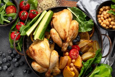 Koyu arkaplanda patates, salata ve sebzeli kızarmış tavuk. Üst görünüm.