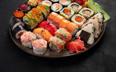 Çeşitli suşi nigiri ve maki büyük set. Ton balıklı, yengeçli, somonlu ve koyu arkaplanda yuvarlanan bir çeşit Japon suşisi. Üst Manzara. Boşluğu kopyala.