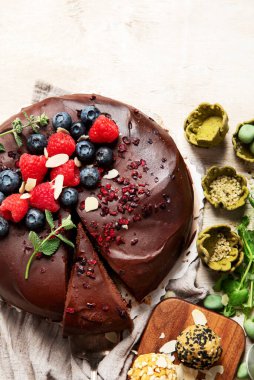 Böğürtlenli vejetaryen çikolatalı pasta ve hafif arka planda atıştırmalıklar. Üst Manzara. Boşluğu kopyala