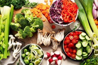 Tabakta ve kâselerde taze kesilmiş sebzeler. Vejetaryen, hafif arka planda vejetaryen yemeği. Üst görünüm.