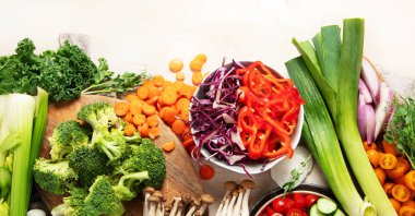 Tabakta ve kâselerde taze kesilmiş sebzeler. Vejetaryen, hafif arka planda vejetaryen yemeği. Üst Manzara. Boşluğu kopyala.