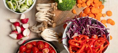 Tabakta ve kâselerde taze kesilmiş sebzeler. Vejetaryen, hafif arka planda vejetaryen yemeği. Üst Manzara. Panorama.