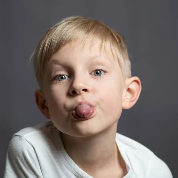 Студийный Портрет Голубоглазого Белокурого Белого Мальчика Смотрящего Камеру Высовывающего Язык — стоковое фото