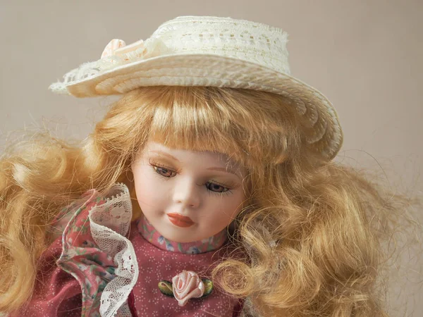 ピンクのドレスと藁帽子に茶色の目で髪を流れるヴィンテージ磁器人形黄金の髪の女の子 — ストック写真