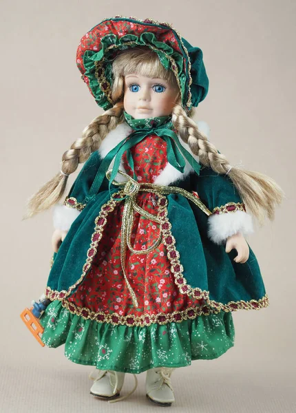 ヴィンテージ磁器人形女の子ブロンドとともに青い目で緑のドレスで赤いトリムと帽子 — ストック写真