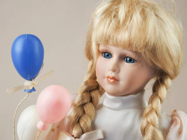 ヴィンテージ磁器人形女の子ブロンドとともに青い目で光のドレスで白 ピンクと青の風船 — ストック写真