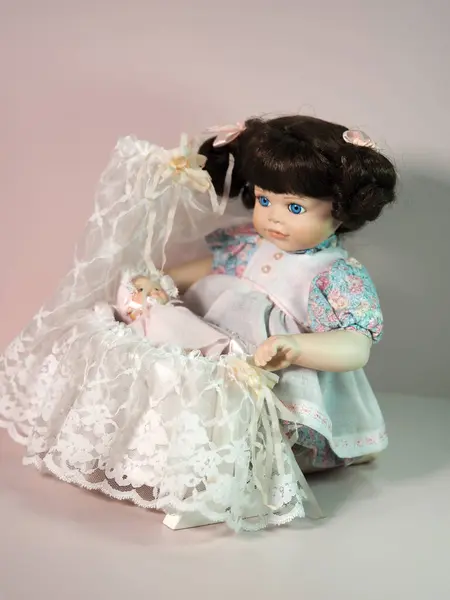 老式饼干瓷娃娃女孩与娃娃在摇篮里玩耍 摇篮里装饰着花边 这个娃娃的名字叫梅根 是由艺术家乔伊斯 雷维为富兰克林 海尔布娃娃设计的 — 图库照片