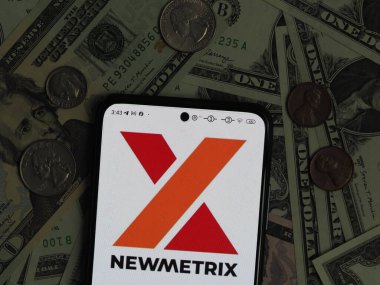 Bavyera, Almanya - 6 Ocak 2024: Bu fotoğraf illüstrasyonunda, arka planda ABD Doları banknotları ve paraları bulunan bir akıllı telefonda Newmetrix logosu görülüyor.