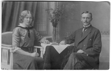 Masanın yanında oturan evli bir çiftin stüdyo resmi. Almanya. Tarih bilinmiyor, yaklaşık 20. yüzyılın başları..