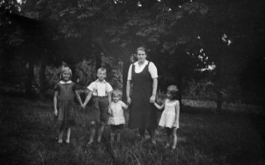 Üzerinde iki kız ve iki erkek çocuğu olan bir kadın kestane ağaçlarının arka planında poz veriyor. Tarih bilinmiyor, 1950 'lerden kalma.