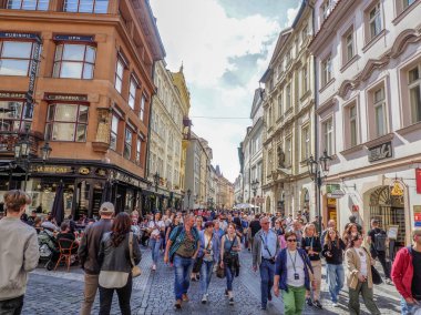 Prag, Çek Cumhuriyeti - 10 Mayıs 2024: Prag 'da tarihi binalar ve kafelerle dolu pitoresk bir caddeyi kalabalık doldurdu. İnsanlar güneşli bir öğleden sonranın tadını çıkarıyor, yerel dükkanları ve restoranları geziyor ve geziyorlar..